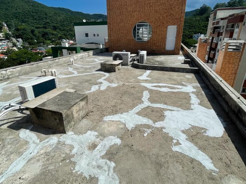 Cobertura de edifício com dezenas de remendos brancos espalhados pela superfície de concreto