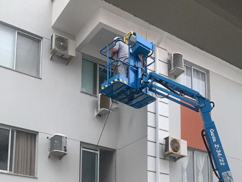 Operador em plataforma elevatória articulada trabalhando na fachada de um edifício residencial em Florianópolis - SC