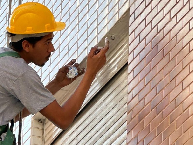 Profissional da HG Engenharia tratando junta e trinca em fachada de pastilha cerâmica de um edifício